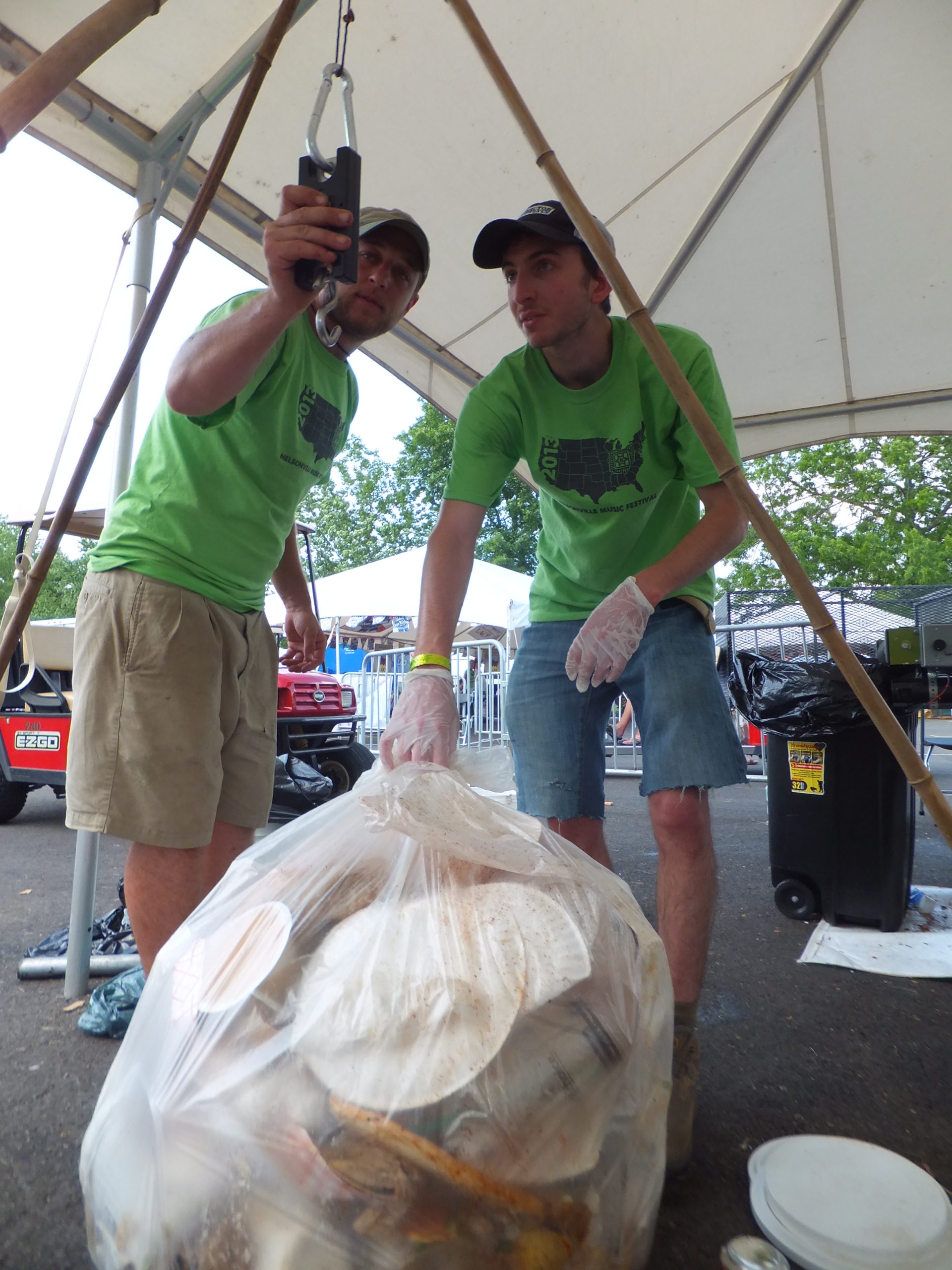 A staffer teaches a volunteer how to weight compostable materials at Nelsonville Music Festival, 2014.