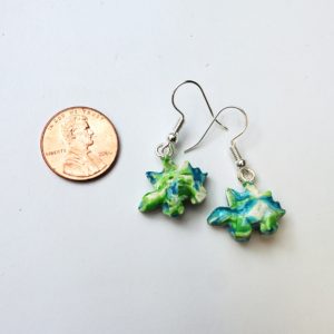 Thick plastic stegosaurus-shaped earring next to a penny to show size. Earrings are half the size.