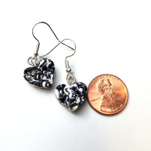 Thick plastic heart-shaped earring next to a penny to show size. Earrings are slightly smaller.